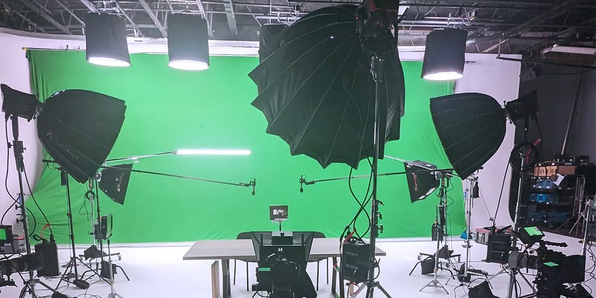 Professional green screen studio setup at Pixthis in Portland, featuring a large green screen backdrop, multiple softbox lights, cameras, and microphones, ideal for video production with lighting setups.