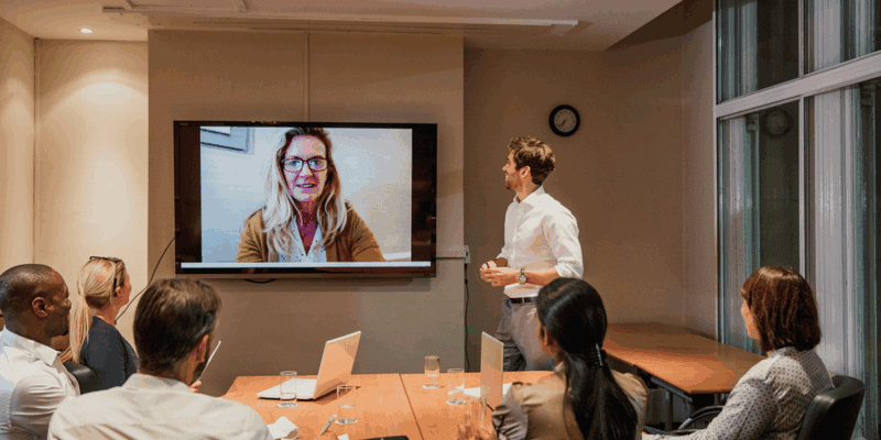 Hybrid meeting in Portland boardroom with large screen showing remote participant, clear audio, and professional AV setup preventing common hybrid failures