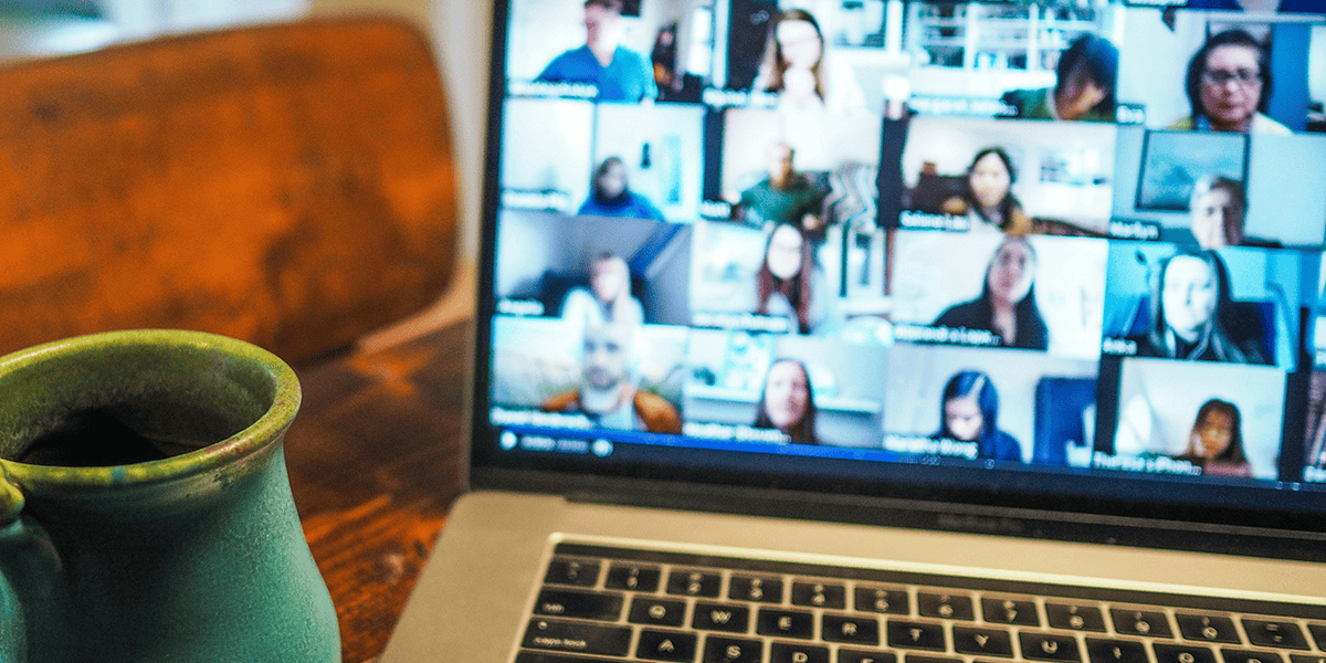 Laptop showing crowded Zoom gallery view with coffee mug 