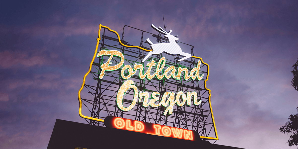 Illuminated Portland Oregon White Stag sign at twilight with Old Town lettering 